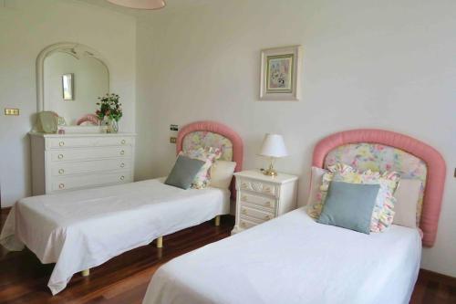 1 dormitorio con 2 camas, tocador y espejo en Villa Airexe. Chalet con piscina y tenis en la Ribeira Sacra, en Taboada