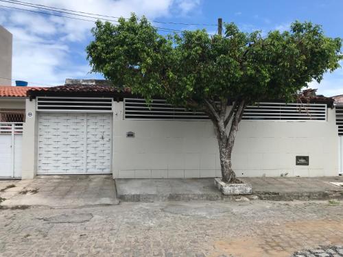 a white garage with a tree in front of it at Pousada Linhares in João Pessoa