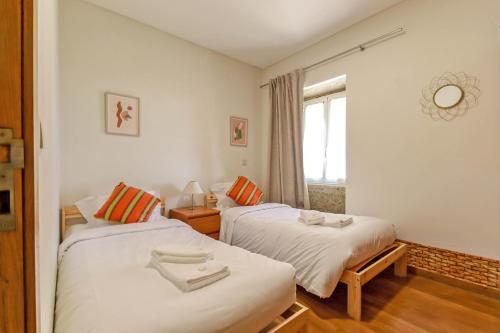 zwei Betten in einem kleinen Zimmer mit Fenster in der Unterkunft Lovely Sunny-House in Viana do Castelo