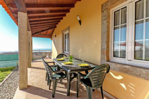 a table and chairs on a patio with a view of the ocean at Lovely Sunny-House in Viana do Castelo