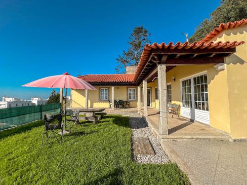 a house with a patio with a table and an umbrella at Lovely Sunny-House in Viana do Castelo