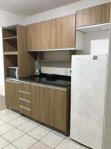 a kitchen with wooden cabinets and a white refrigerator at Pousada Linhares in João Pessoa