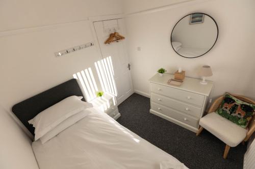 a bedroom with a bed and a chair and a mirror at 68 Glenwood Road in Ellesmere Port