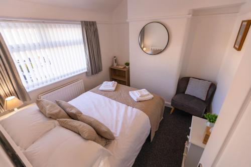 a bedroom with a bed with a mirror and a chair at 68 Glenwood Road in Ellesmere Port