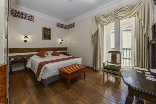 a bedroom with a bed and a table and a chair at La Casona Real Cusco in Cusco