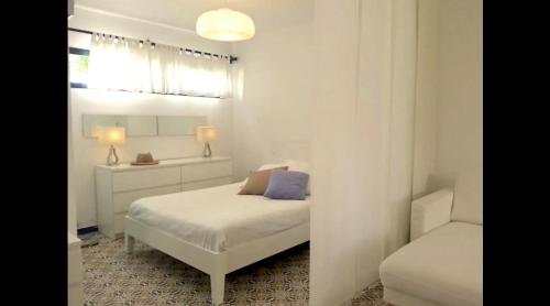 a white bedroom with a bed and a chair at Bungalow 4 Binisafua in Binisafua