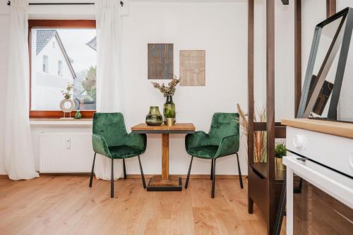 a dining room with a table and green chairs at Kurzzeitglück 24h Self Check-In MH02 in Mülheim an der Ruhr