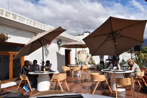 Parador Monte Carmelo في مدينة أواكساكا: مجموعة من الناس يجلسون على طاولات مزودة بمظلات
