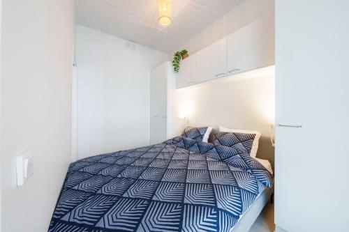 een slaapkamer met een bed met een blauw en wit dekbed bij Cozy 1-bed super flat, 20 min to Helsinki/Airport in Vantaa