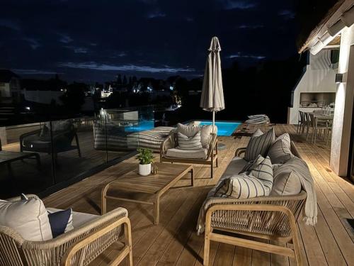 a patio with couches and a table and an umbrella at Laid back luxury canal house in St Francis Bay