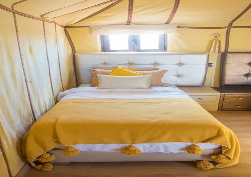 a bedroom with a large bed with a yellow blanket at Desert Luxury Tented & Activities in Hassilabied