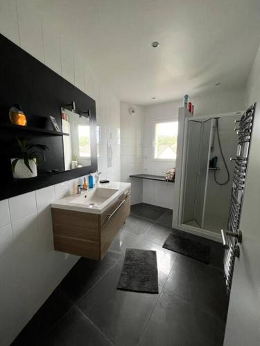 une salle de bain blanche avec un lavabo et une douche dans l'établissement Accès direct plage 100m, à Jullouville