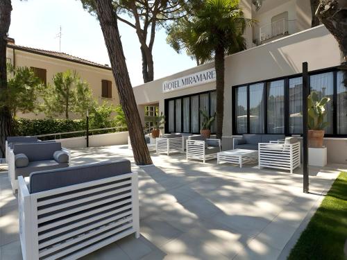 un bâtiment avec des bancs blancs devant lui dans l'établissement Hotel Miramare - SPA & Suites - Breakfast & Brunch Until 13-00, à Cervia