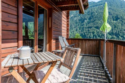 una mesa de madera y sillas en el porche de una cabaña en Silvretta Nova, en Sankt Gallenkirch