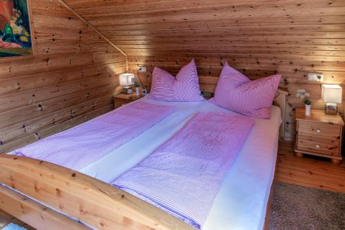 Cama grande en habitación de madera con almohadas rosas en Silvretta Nova, en Sankt Gallenkirch