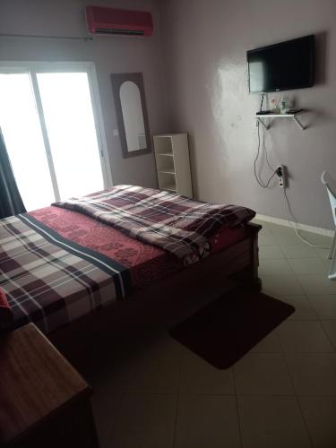 um quarto com uma cama com um cobertor xadrez e uma janela em Peace N Quiet aux Almadies em Dakar