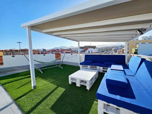 St George's Apartments - Gran Canaria في تيلدي: فناء على أريكة زرقاء وطاولات على السطح