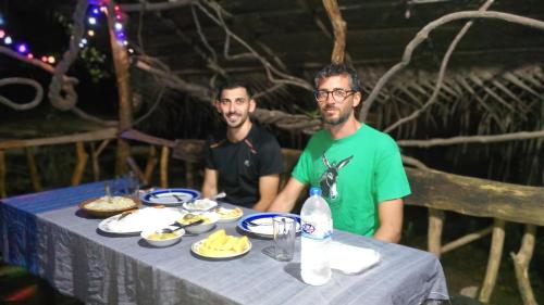 two men sitting at a table with food on it at Relax Nature Villa in Sigiriya