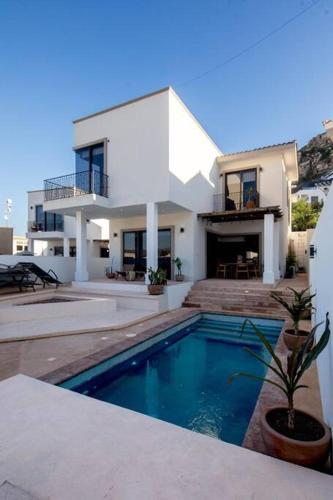 a house with a swimming pool in front of a house at Casa Gallo, Heated Pool, Exclusive Beach & Great Location in Cabo San Lucas
