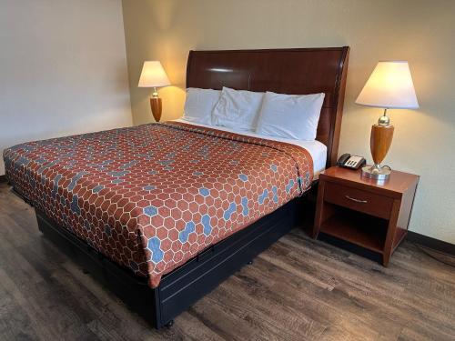 a hotel room with a bed and a night stand with a phone at Desert Sands Inn & Suites in Albuquerque