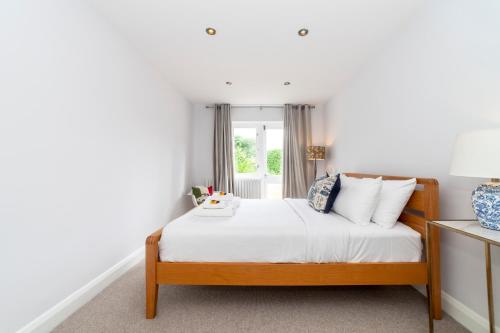 a bedroom with a bed with white sheets and a window at Hidden treasure 2 BR ground floor apt, Brentford in Brentford