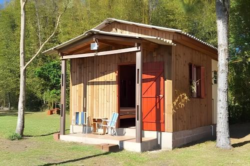 a small wooden cabin with a red door and chairs at WiFi x Sítio x Fogueira x 7km Pq de Rodeio x 6km Estr do Mar x Churrasqueira in Osório