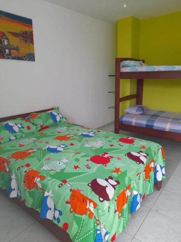 un dormitorio con un edredón verde con animales. en FAMILIA REINOSO, en Tonsupa