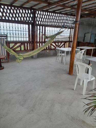 a room with chairs and a hammock in a building at FAMILIA REINOSO in Tonsupa