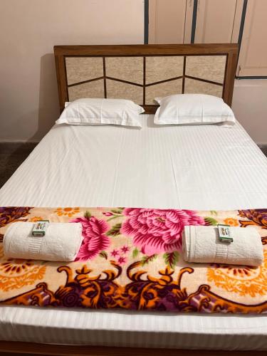 a bed with two pillows and two towels on it at Vintage Walls Homestay in Hampi