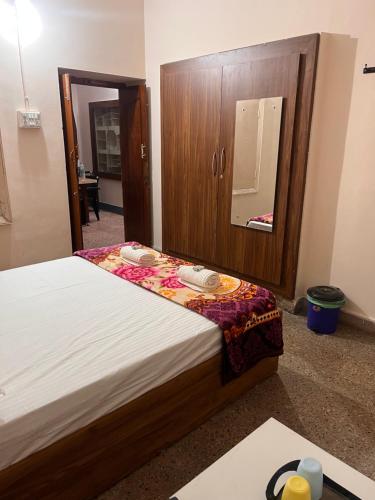 a bedroom with a bed with a wooden cabinet and a mirror at Vintage Walls Homestay in Hampi
