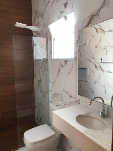 a bathroom with a toilet and a sink and a mirror at Pousada Refúgio das Flores in Ubatuba