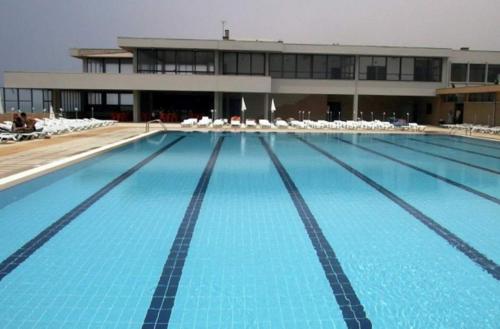 uma grande piscina com cadeiras e um prédio em Varandas do Mar em Arcozelo