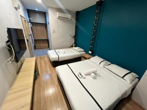 a room with two beds and a blue wall at Smile Hotel Wangsa Maju in Kuala Lumpur