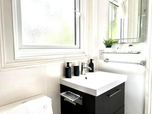 a bathroom with a white sink and a window at Spacious 2-Bed House 20 mins from Central London in London