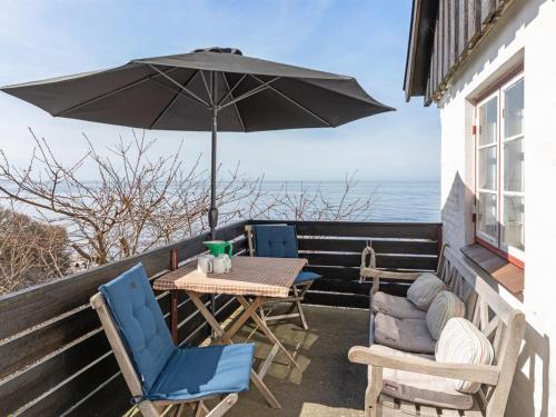 a table and chairs on a balcony with an umbrella at Holiday Home Asgot - 15m from the sea in Bornholm by Interhome in Hasle