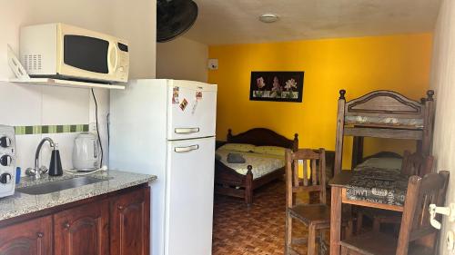 a kitchen with a white refrigerator and a bed at Complejo Sol Palmeras in Mar de Ajó