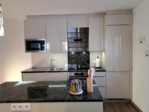 una cucina con armadi bianchi e piano di lavoro nero di Apartment Alpina-3 by Interhome a Finkenberg