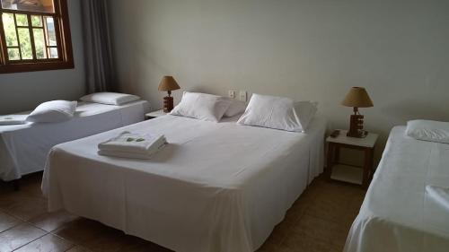 a bedroom with two beds with white sheets at Pousada das Pedras Paraty -RJ in Paraty