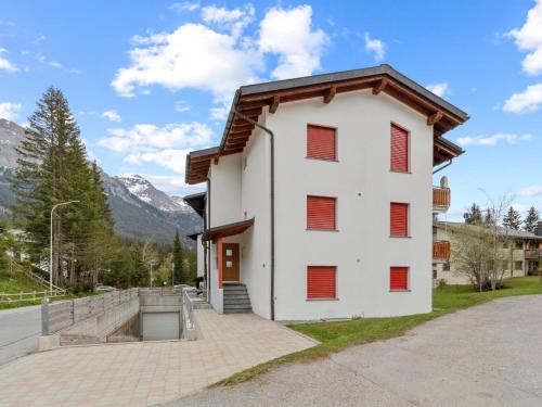 a white building with red shutters on it at Apartment Auarara by Interhome in Lenzerheide