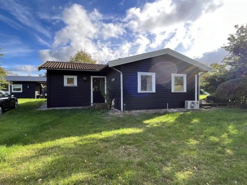 uma pequena casa preta com um jardim de relva em Holiday Home Janna - 1-4km from the sea in Sealand by Interhome em Vig