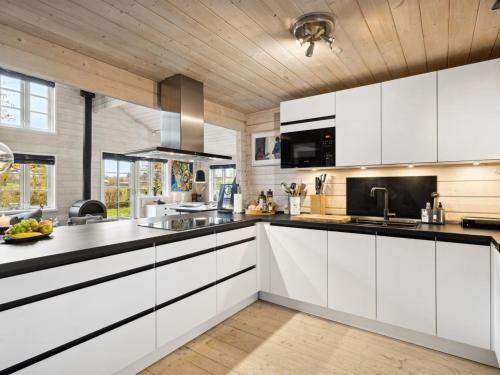 een keuken met witte kasten en zwarte aanrechtbladen bij Holiday Home Anemarie - all inclusive - 400m from the sea by Interhome in Karrebæksminde