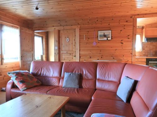 ein braunes Ledersofa in einem Zimmer mit einer Holzwand in der Unterkunft Chalet Kil-Ukru by Interhome in Ovronnaz