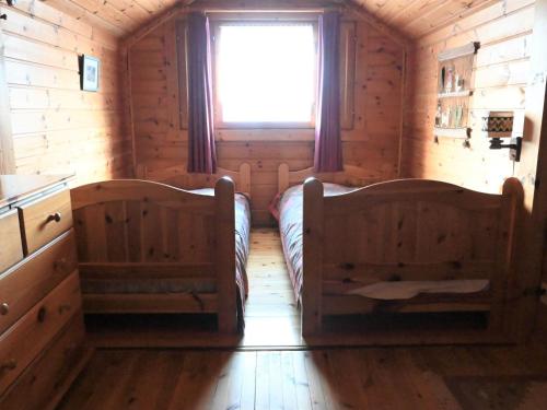 sypialnia w drewnianym domku z 2 łóżkami i oknem w obiekcie Chalet Kil-Ukru by Interhome w mieście Ovronnaz