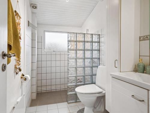 a white bathroom with a toilet and a shower at Holiday Home Felis - 75m from the sea by Interhome in Martofte