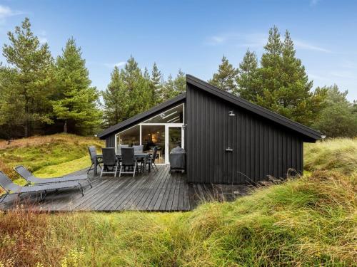 ein schwarzes Haus auf einem Hügel mit einer Terrasse in der Unterkunft Holiday Home Emila - 2-2km from the sea in Western Jutland by Interhome in Bolilmark