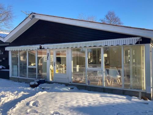 un porche cerrado con puertas de cristal en la nieve en Holiday Home Senja - 450m from the sea in NE Jutland by Interhome, en Hals