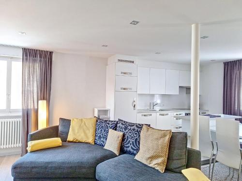 ein Wohnzimmer mit einem blauen Sofa und einer Küche in der Unterkunft Apartment Violettes-Vacances A-B-C-7 by Interhome in Crans-Montana