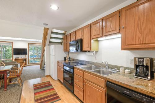 a kitchen with wooden cabinets and a sink at Palisades Tahoe Lodge Rentals Studio Loft #306 in Olympic Valley