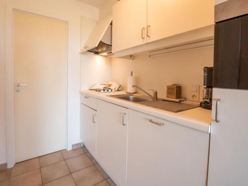 uma cozinha com armários brancos e um lavatório em Apartment Marlene by Interhome em De Haan
