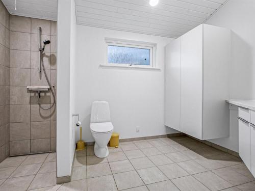 uma casa de banho branca com um WC e uma janela em Holiday Home Majvor - 200m from the sea in NE Jutland by Interhome em Hadsund
